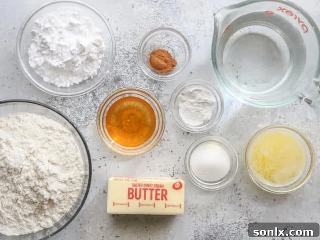 A collection of ingredients for fry bread and cinnamon honey butter, including flour, butter, honey, and cinnamon, arranged on a wooden surface.