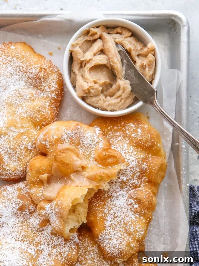 A close-up of a piece of warm fry bread generously slathered with creamy cinnamon honey butter, highlighting its inviting texture and delicious topping.