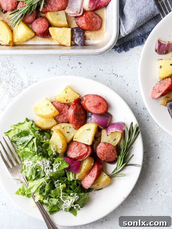 A close-up shot of the cooked sheet pan sausage and potatoes, showing crispy edges and tender insides, garnished with fresh herbs.