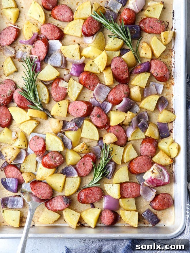 A serving of sheet pan sausage and potatoes on a plate, showcasing the golden color and a side of green beans.