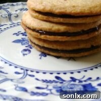Golden brown toasted coconut shortbread cookies, some with chocolate ganache filling, on a cooling rack.