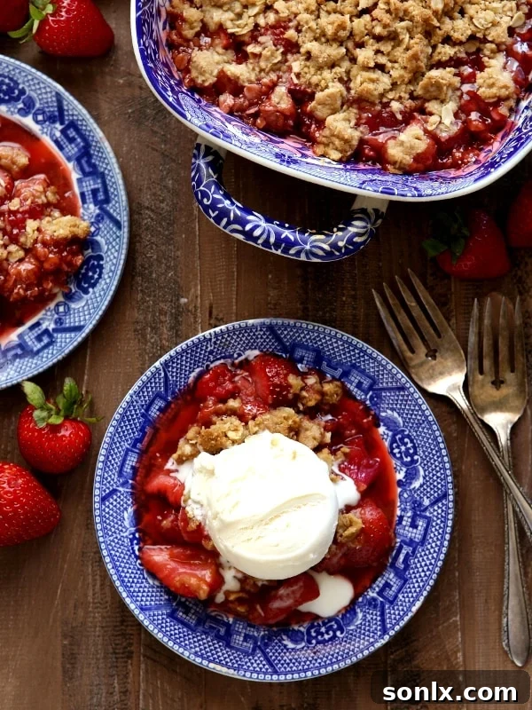 A rustic Strawberry, Rhubarb, and Raspberry Crisp in a baking dish, with a golden crumb topping.
