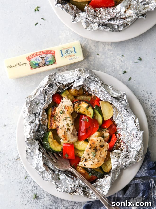 A perfectly cooked chicken and veggie tin foil dinner, unwrapped and ready to be eaten, showcasing tender chicken and vibrant vegetables.