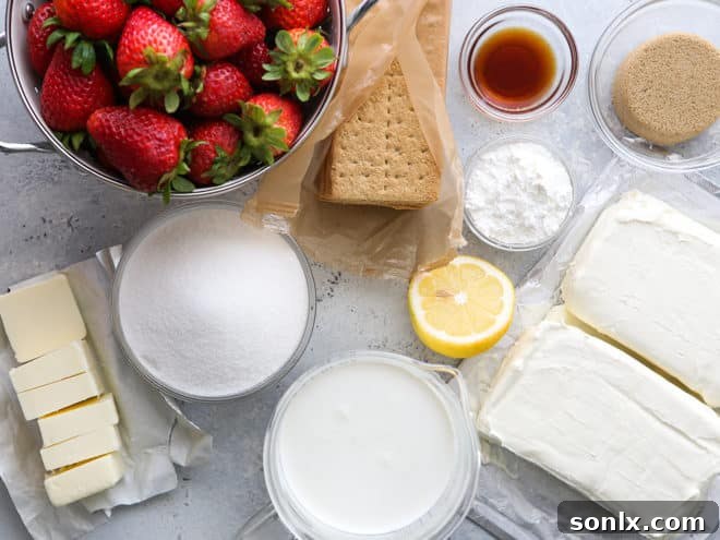 A selection of fresh ingredients laid out for making no-bake strawberry cheesecake bars, including strawberries, cream cheese, and graham crackers