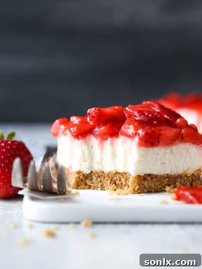 Three perfectly sliced no-bake strawberry cheesecake bars, showing the thick creamy layer and fruit topping, ready to be served