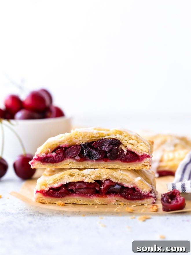 cherry hand pies cut in half and stacked, showcasing flaky crust and juicy filling