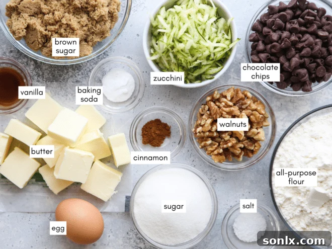 Collection of fresh ingredients for baking zucchini chocolate chip cookies: butter, sugars, egg, vanilla, flour, zucchini, chocolate chips, and walnuts