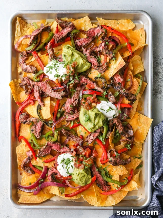 Sheet pan loaded with vibrant steak fajita nachos, ready to serve.