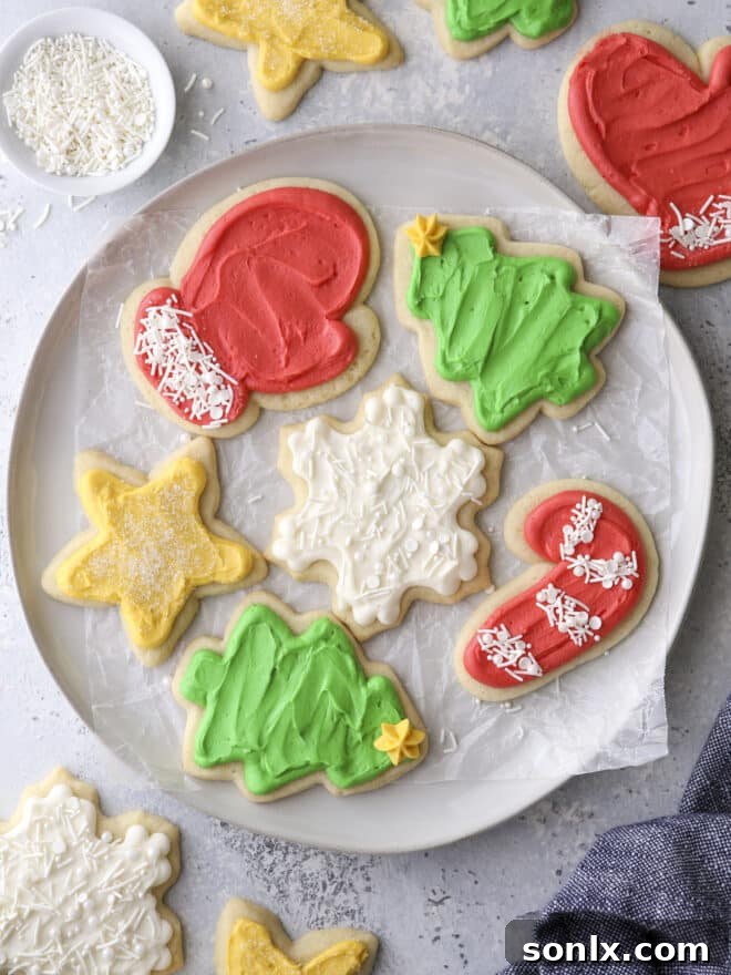 A plate brimming with beautifully decorated frosted sugar cookie cut-outs, showcasing various festive shapes and vibrant frosting colors.