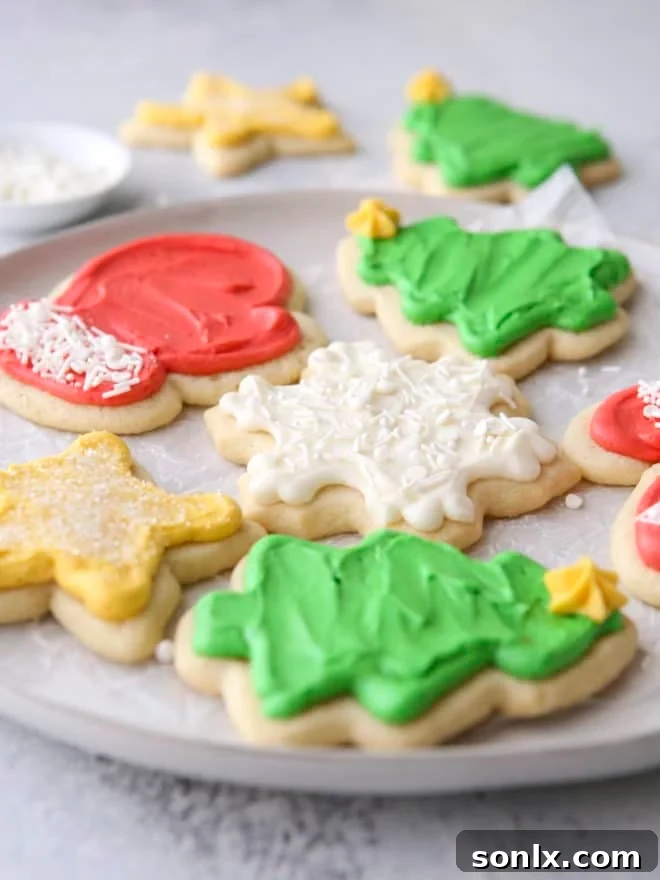 A close-up side view of exquisitely frosted sugar cookie cut-outs on a plate, highlighting their perfect shape and smooth, inviting frosting.