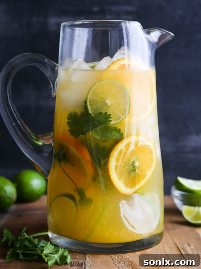 Refreshing Margarita Sangria cocktail in a pitcher with lime and orange slices