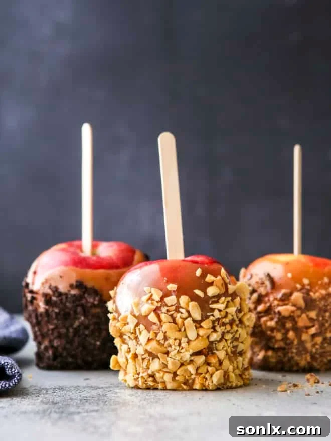 Homemade caramel apples generously coated with crushed Oreos, nuts, and candy bar pieces.