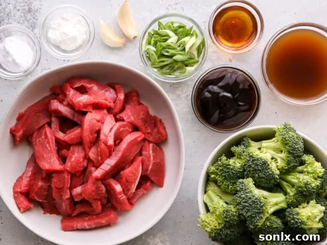 Fresh ingredients for Beef and Broccoli Stir Fry laid out on a cutting board, including sliced beef, broccoli florets, garlic, and green onions.