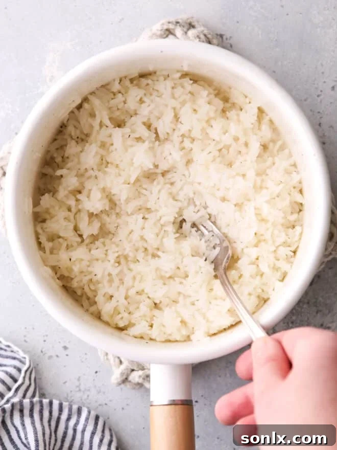 Fluffing steamed rice in a pot with a fork