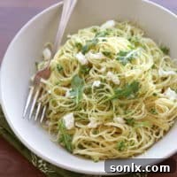 Arugula Pesto Pasta with Ricotta Cheese in a white bowl, garnished with fresh arugula.