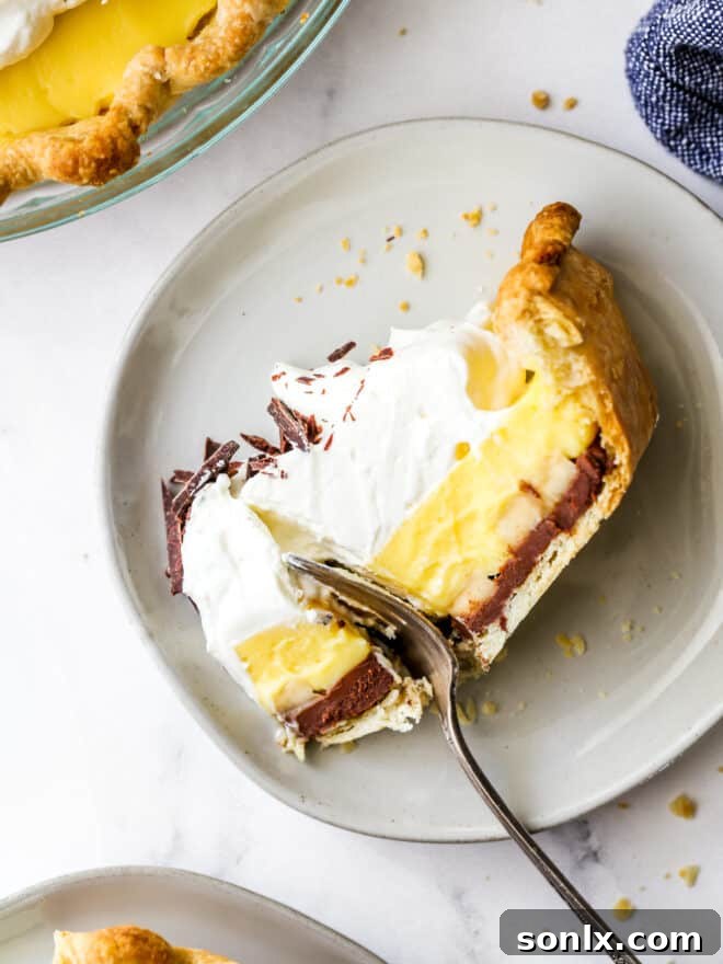 A person taking a bite out of a generous slice of Chocolate Banana Cream Pie, showing the perfect layers and creamy texture.