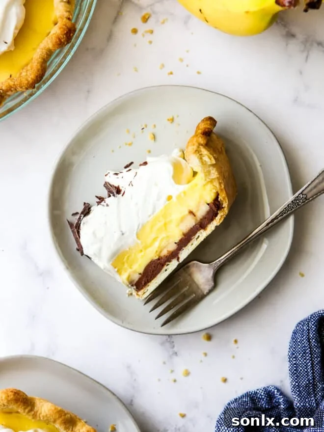 A perfectly portioned slice of Chocolate Banana Cream Pie on a white plate, highlighting the distinct layers and inviting presentation.