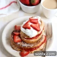 Gourmet Strawberry Rhubarb Stuffed French Toast topped with whipped cream and fresh strawberries