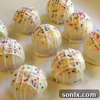Beautifully decorated cake truffles arranged artfully on a serving dish.