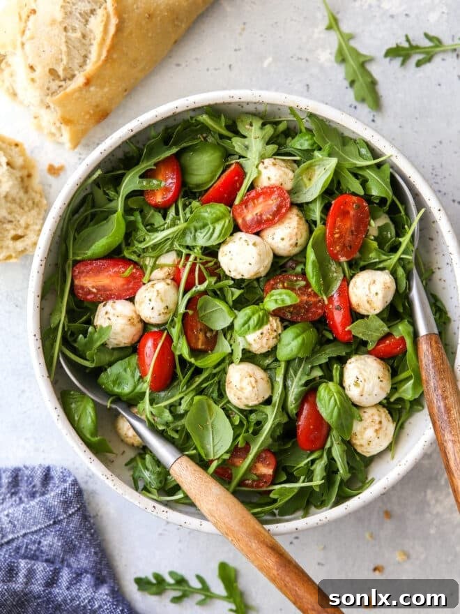 Arugula Caprese Salad served in a rustic bowl, accompanied by crusty bread, ready to be enjoyed.