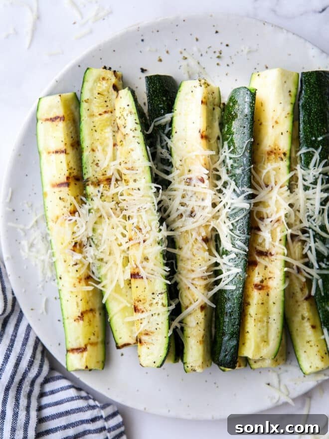 close up of grilled parmesan zucchini on a plate, highlighting texture and cheese