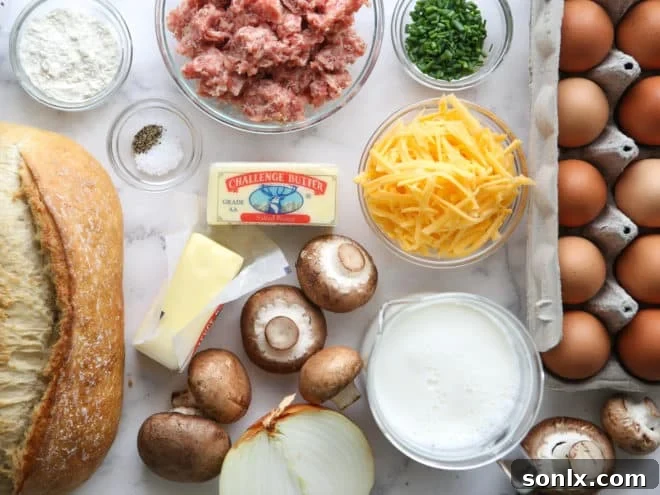A collection of fresh ingredients laid out for preparing the sausage and mushroom breakfast casserole, including sausage, mushrooms, onions, eggs, bread, and cheese.