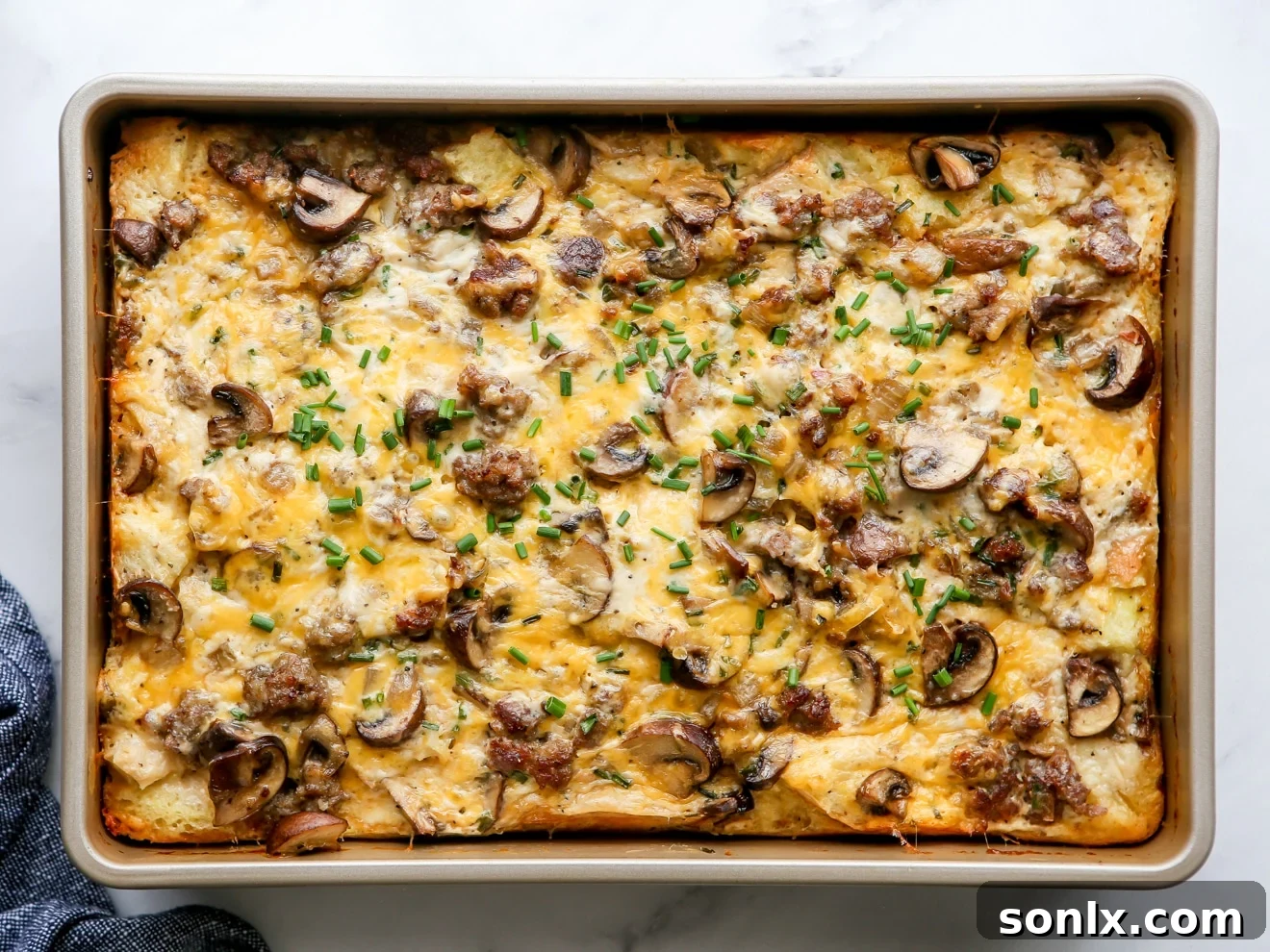 A beautifully baked sausage and mushroom breakfast casserole, golden brown and puffed, fresh out of the oven, ready to be served.