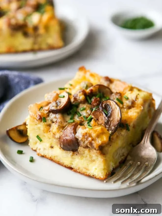 A close-up view of a single slice of sausage and mushroom breakfast casserole, highlighting its layers and texture.