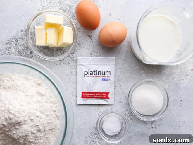 Basic ingredients laid out for making dinner rolls: flour, yeast, milk, butter, eggs, sugar, salt