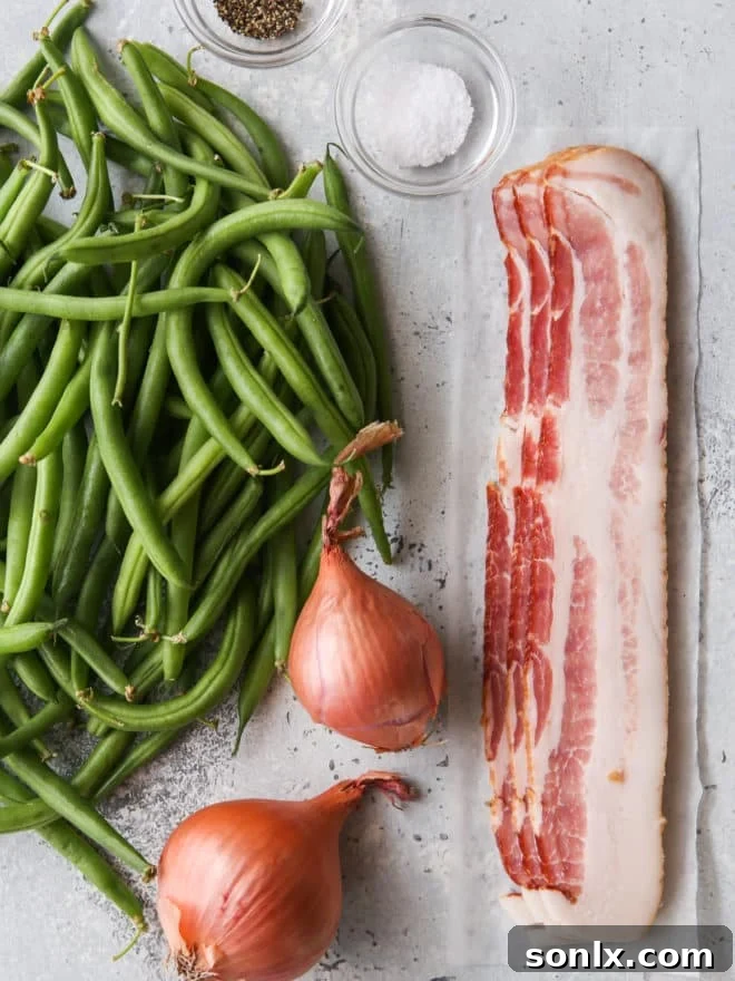 Layout of fresh ingredients for green beans with crispy shallots and bacon, including fresh green beans, whole shallots, raw bacon strips, and a stick of butter.