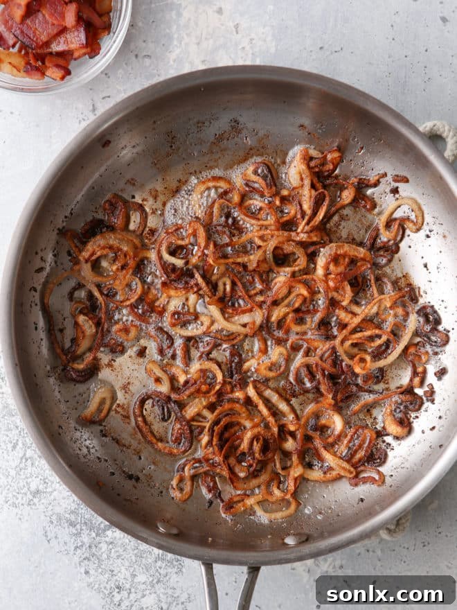 Crispy golden-brown shallots sizzling in a pan with residual bacon grease.