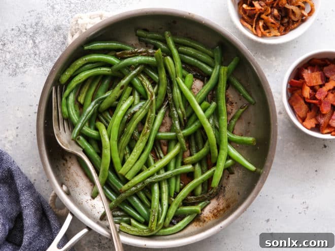 Sautéed green beans in a pan, with a bowl of crispy bacon and another bowl of golden shallots waiting to be combined.