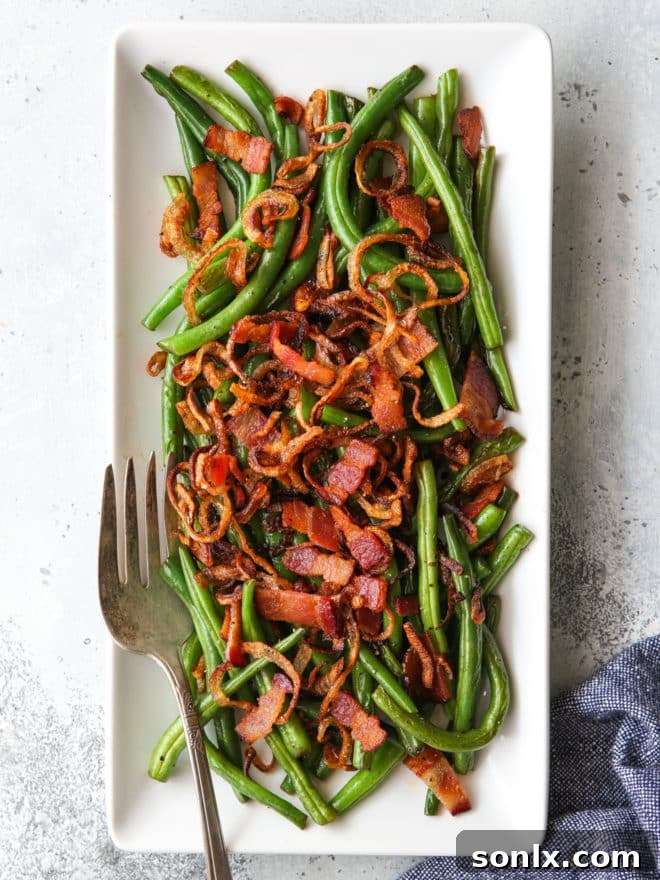 A stunning platter of green beans with crispy shallots and bacon, perfectly arranged with a fork resting beside it, inviting a delicious serving.