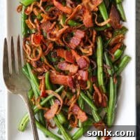 closeup of green beans with crispy shallots and bacon on a platter with fork