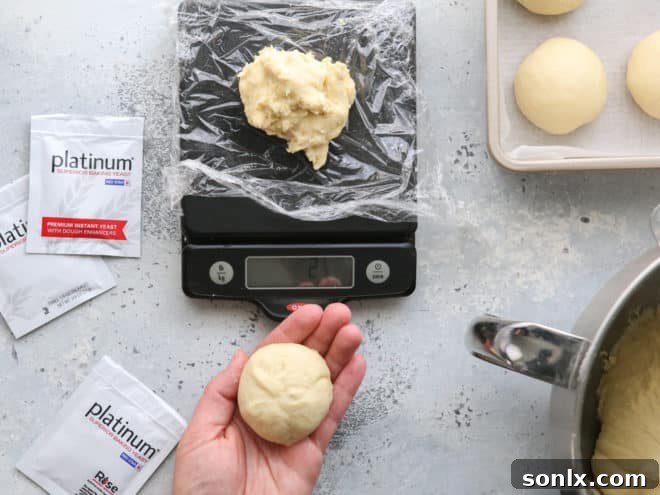 A baker shaping homemade sandwich rolls by hand on a counter