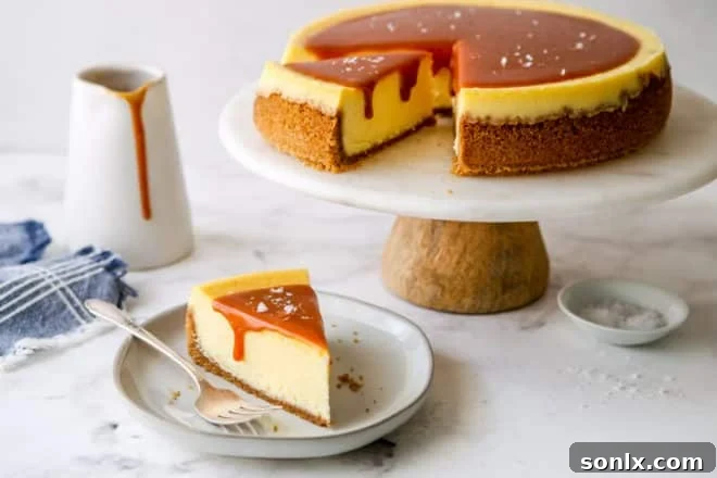 slice of salted caramel cheesecake on a plate with cake stand in background
