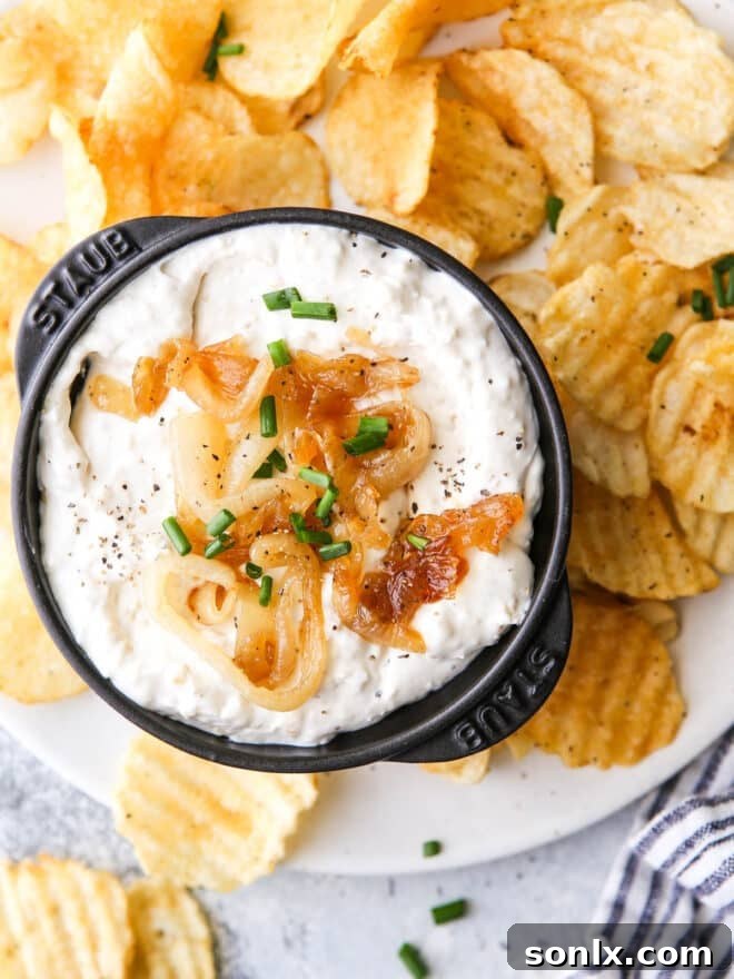 Rich Caramelized Onion Dip 2 A bowl of creamy French onion dip, garnished with caramelized onions, served with golden potato chips on the side.