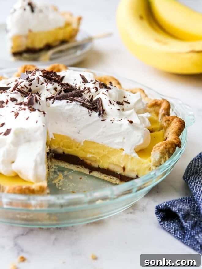 A slice taken out of a chocolate-bottom banana cream pie, revealing its tempting layers of chocolate crust, creamy banana filling, and whipped cream.