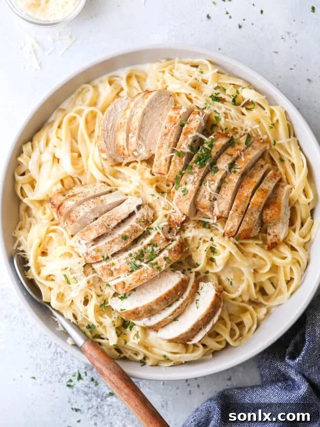 A bowl of creamy chicken fettuccine alfredo, garnished with parsley.