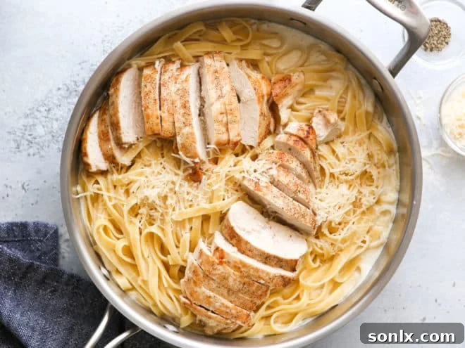 Mixing chicken fettuccine alfredo in a large skillet.