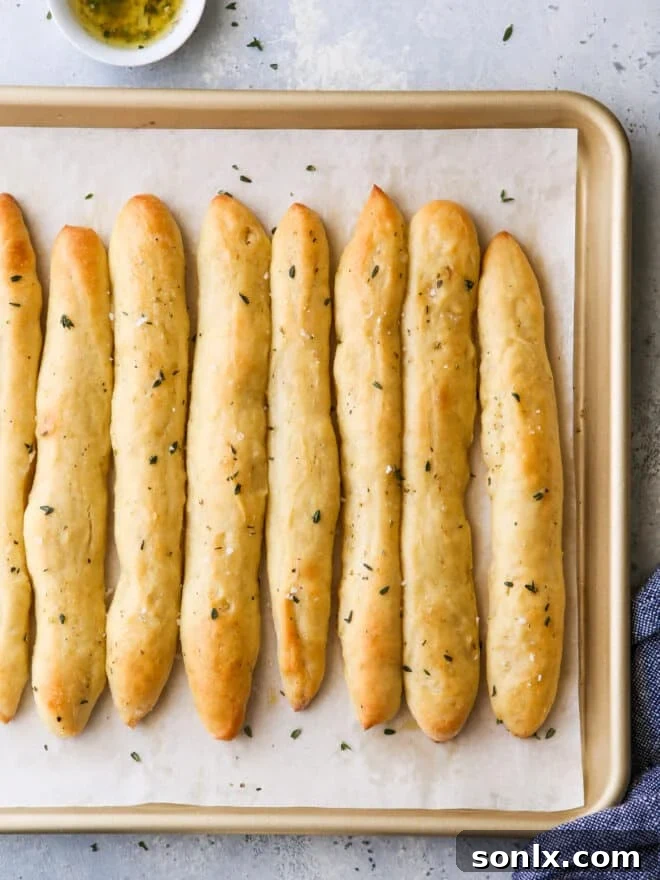 Baked no-knead breadsticks, golden brown and glistening with garlic herb butter