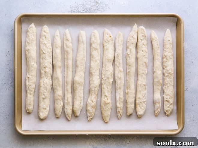 Breadstick strips arranged on a parchment-lined baking sheet, ready for baking