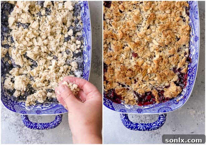 Blueberry crisp filling in a baking dish with the almond-oat topping partially sprinkled over it, ready for baking.