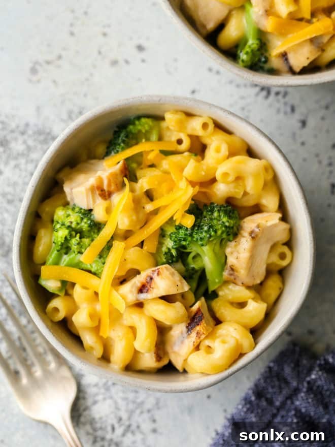 A serving of chicken broccoli macaroni and cheese in a bowl with a fork, ready to eat