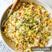 A bowl of creamy macaroni salad with a large serving spoon, ready to be enjoyed.