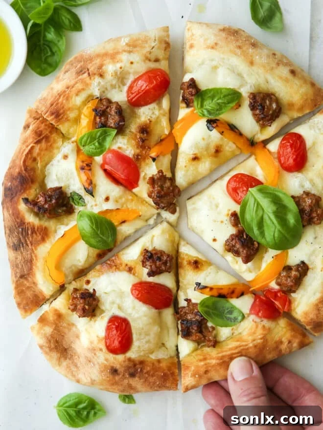 Delicious Italian sausage pizza with roasted peppers, tomatoes, and basil
