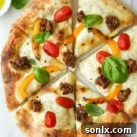 A hand reaching for a slice of Italian sausage pizza