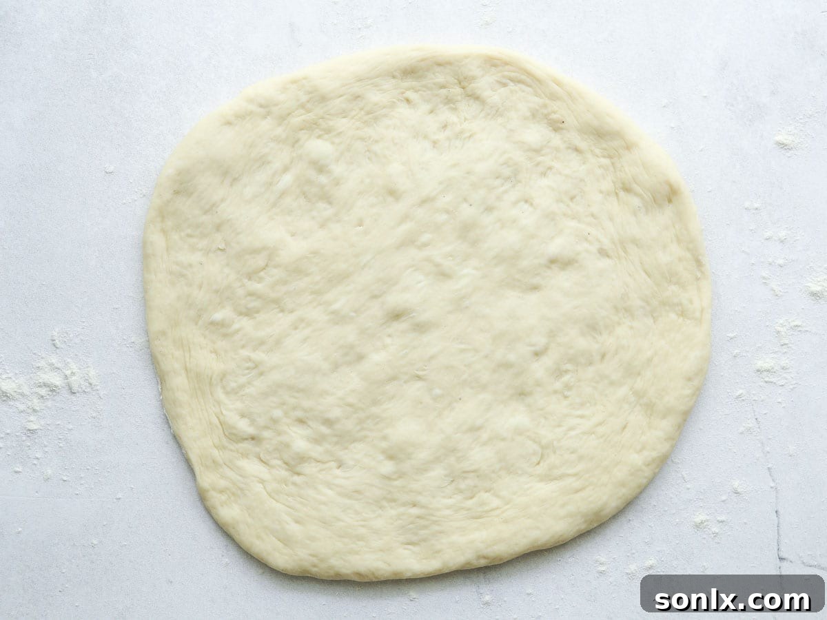 Rolled out pizza dough on a floured counter, ready for toppings