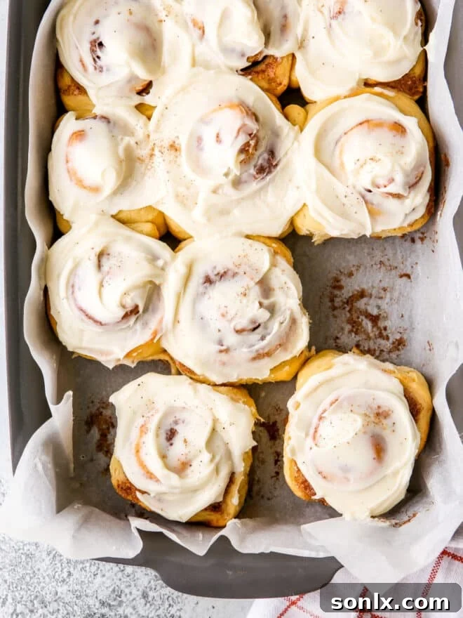 A close-up of a single Eggnog Cinnamon Roll with its rich, swirled interior and melting icing, isolated on a white background.