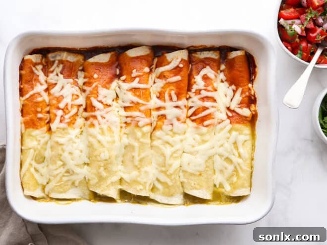 A freshly baked dish of red and green chicken enchiladas, topped with melted cheese and ready for serving.